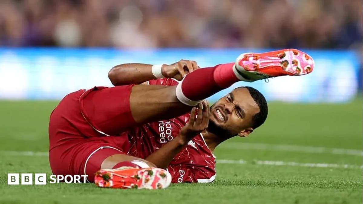 Player in red jersey lying on ground in pain Player in red jersey lying on ground in pain