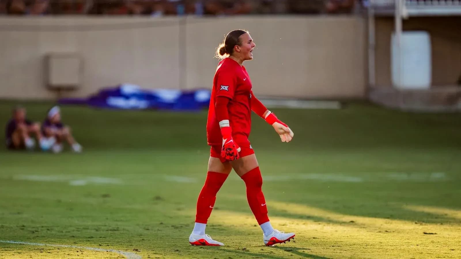Goalkeeper in red uniform walking on the field Goalkeeper in red uniform walking on the field