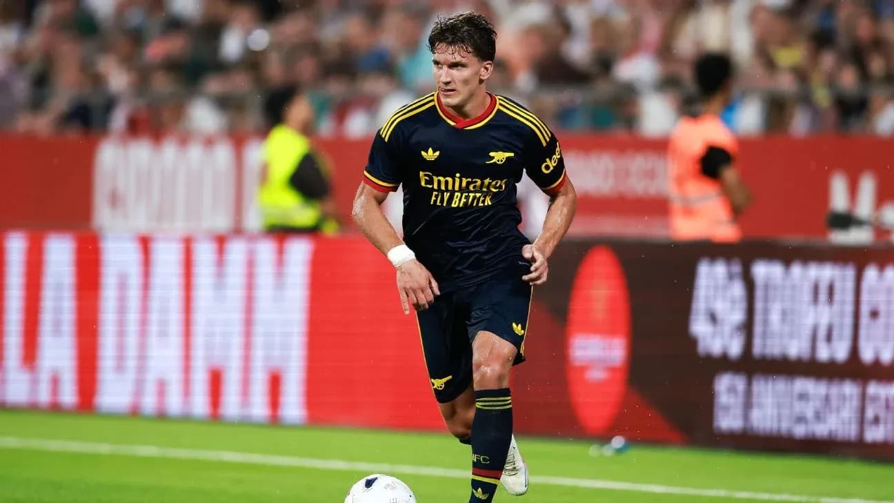 Player in Arsenal kit dribbling the ball on pitch Player in Arsenal kit dribbling the ball on pitch