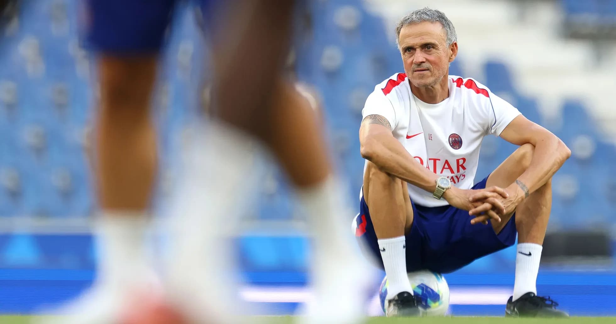 Coach squatting on pitch during training session Coach squatting on pitch during training session