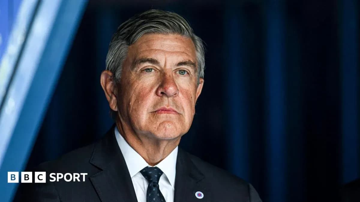 Man in suit standing in front of blue backdrop Man in suit standing in front of blue backdrop