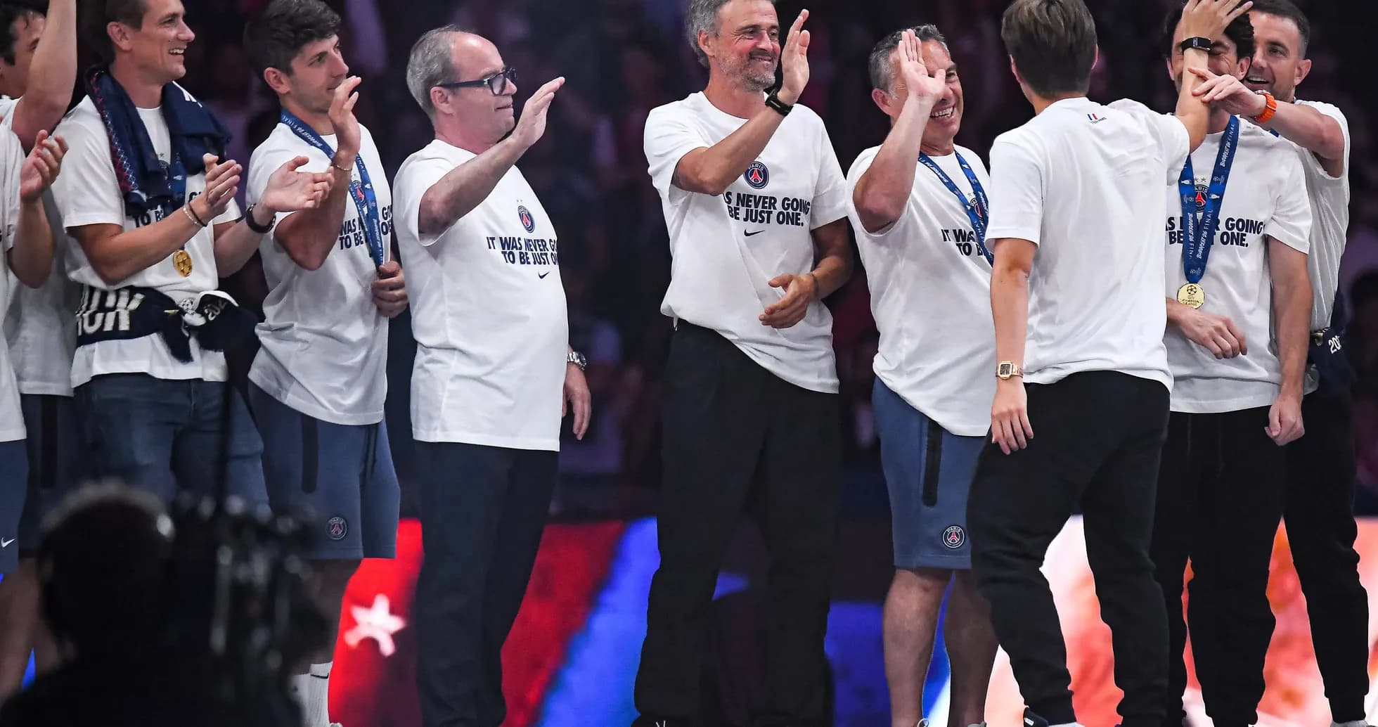 Coaches and staff celebrating on stage with medals Coaches and staff celebrating on stage with medals