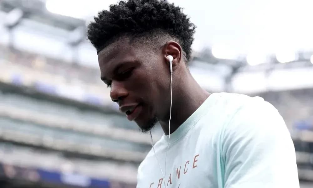 Player wearing earbuds on stadium sidelines Player wearing earbuds on stadium sidelines