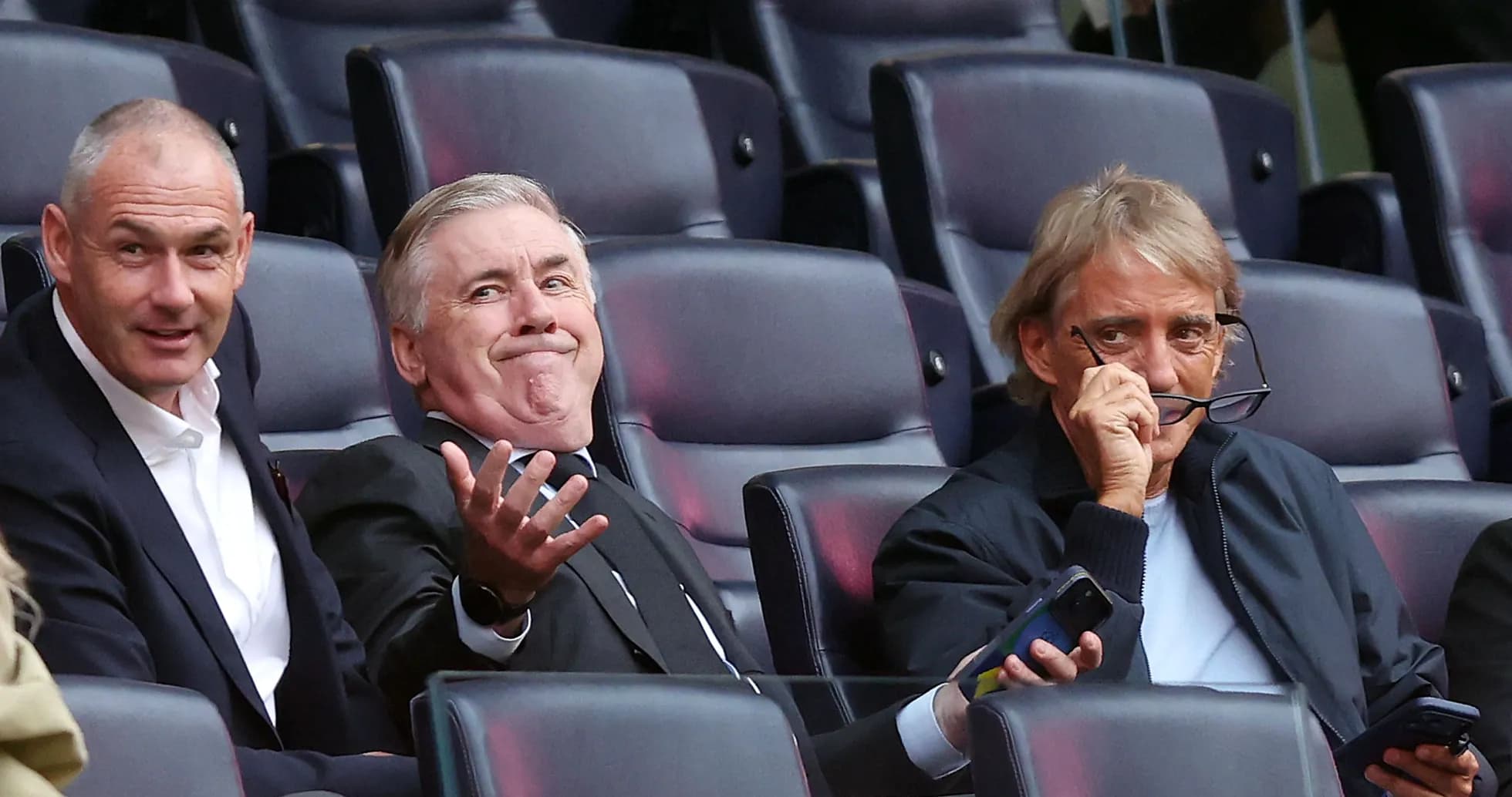 Three men seated in stadium, watching event Three men seated in stadium, watching event