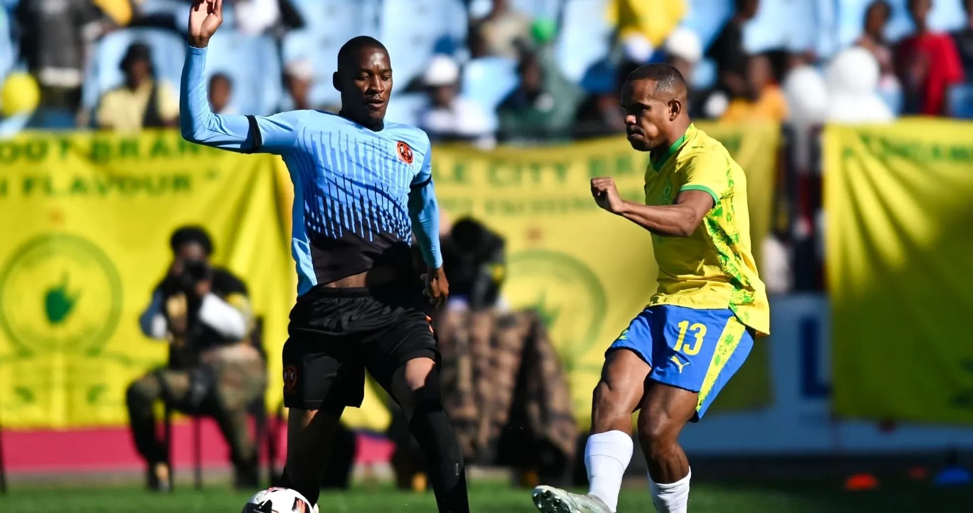 Player in yellow kicking ball, opponent defending Player in yellow kicking ball, opponent defending