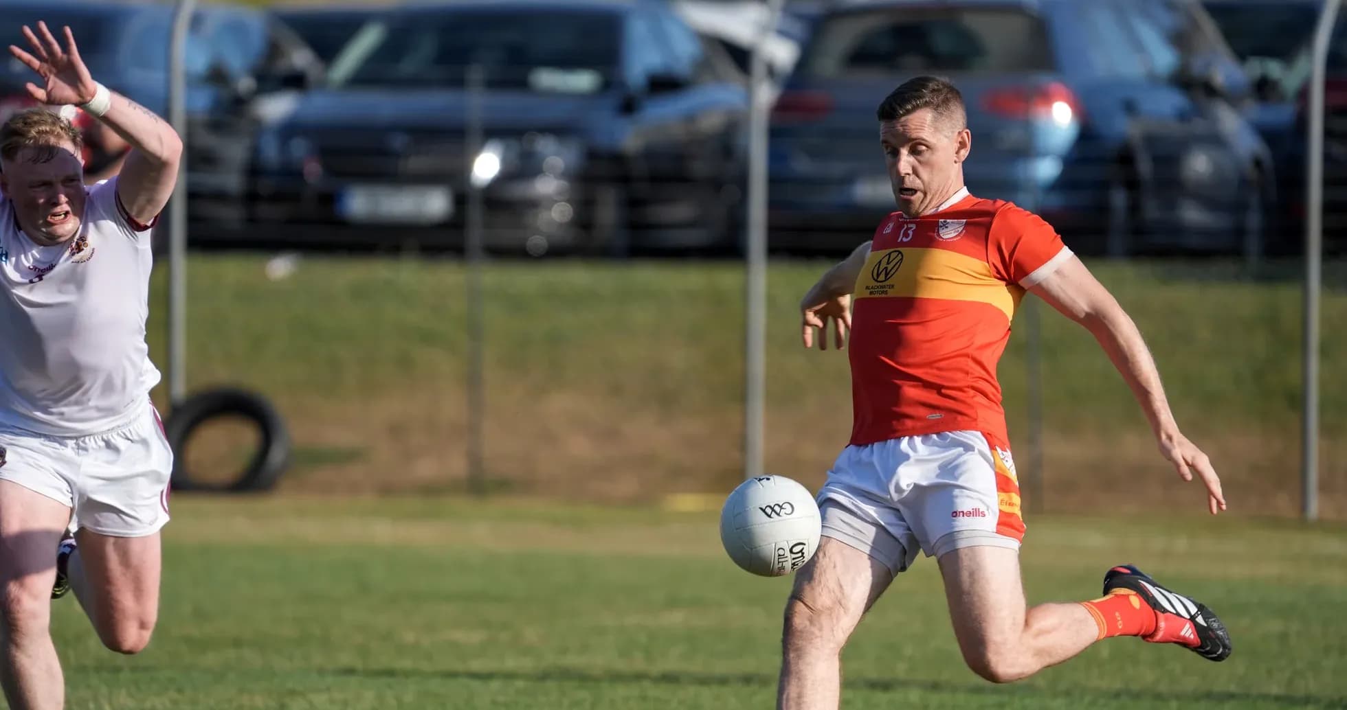Player kicking a Gaelic football during match Player kicking a Gaelic football during match