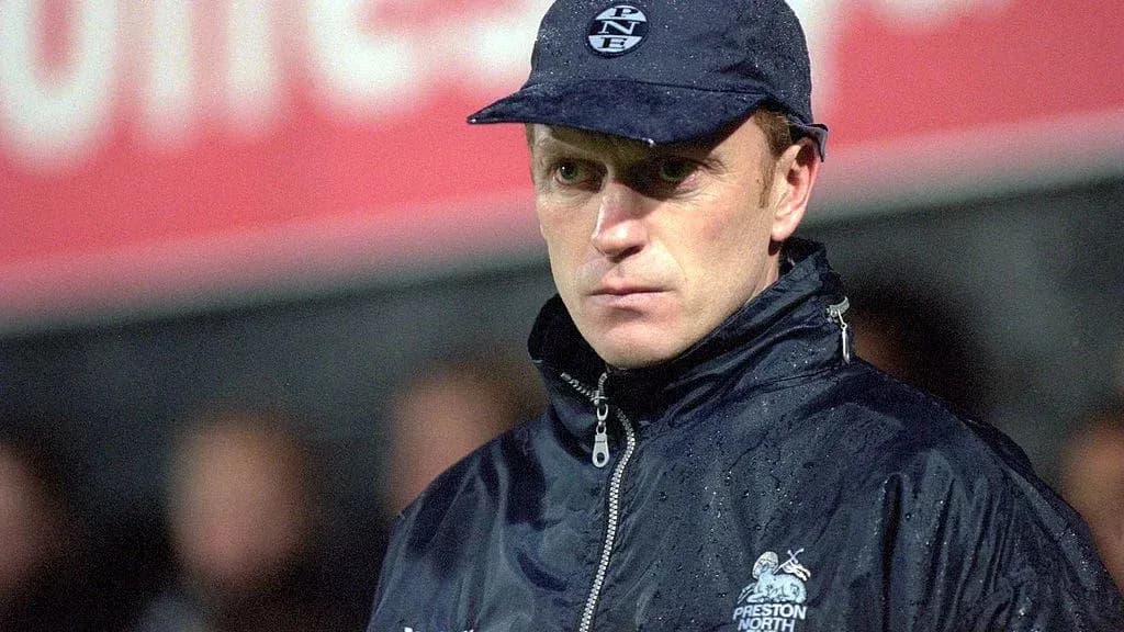 Manager observing match in rain with cap Manager observing match in rain with cap