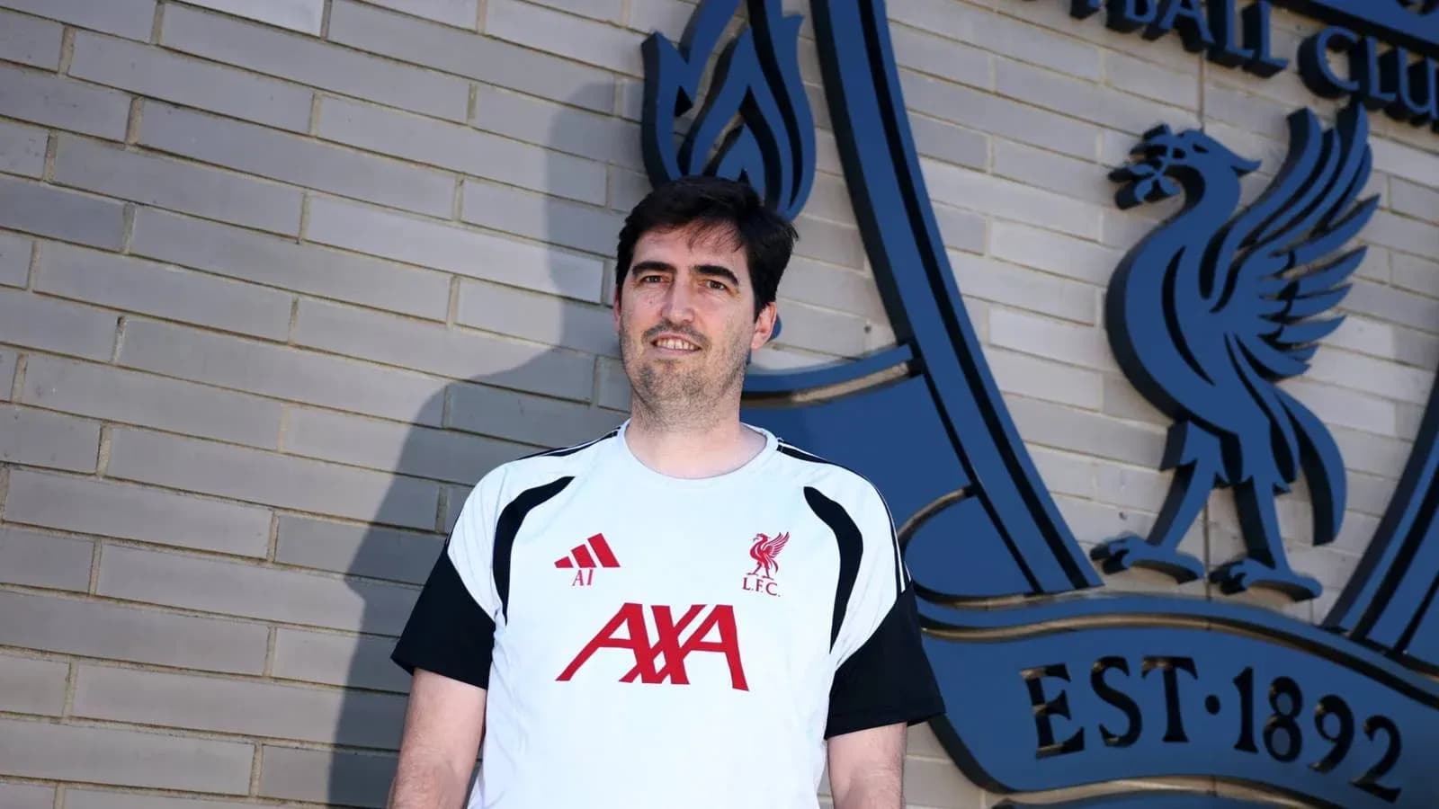 Person in Liverpool FC training kit at club logo Person in Liverpool FC training kit at club logo