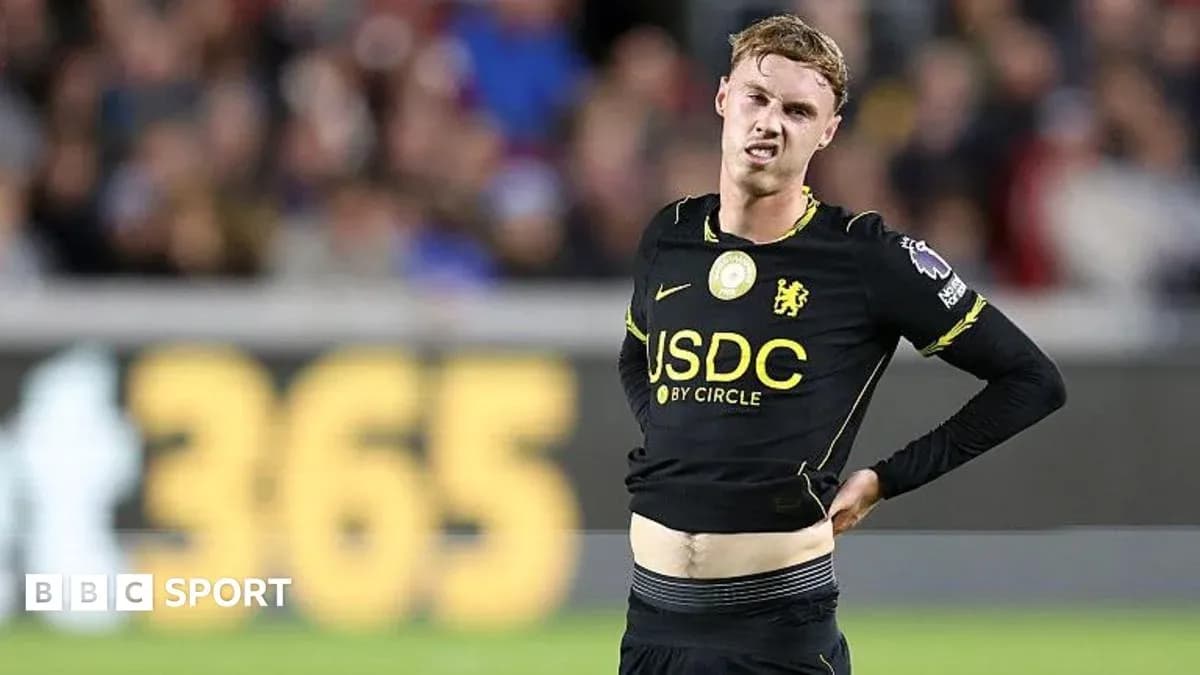 Player in black kit holding stomach during match Player in black kit holding stomach during match