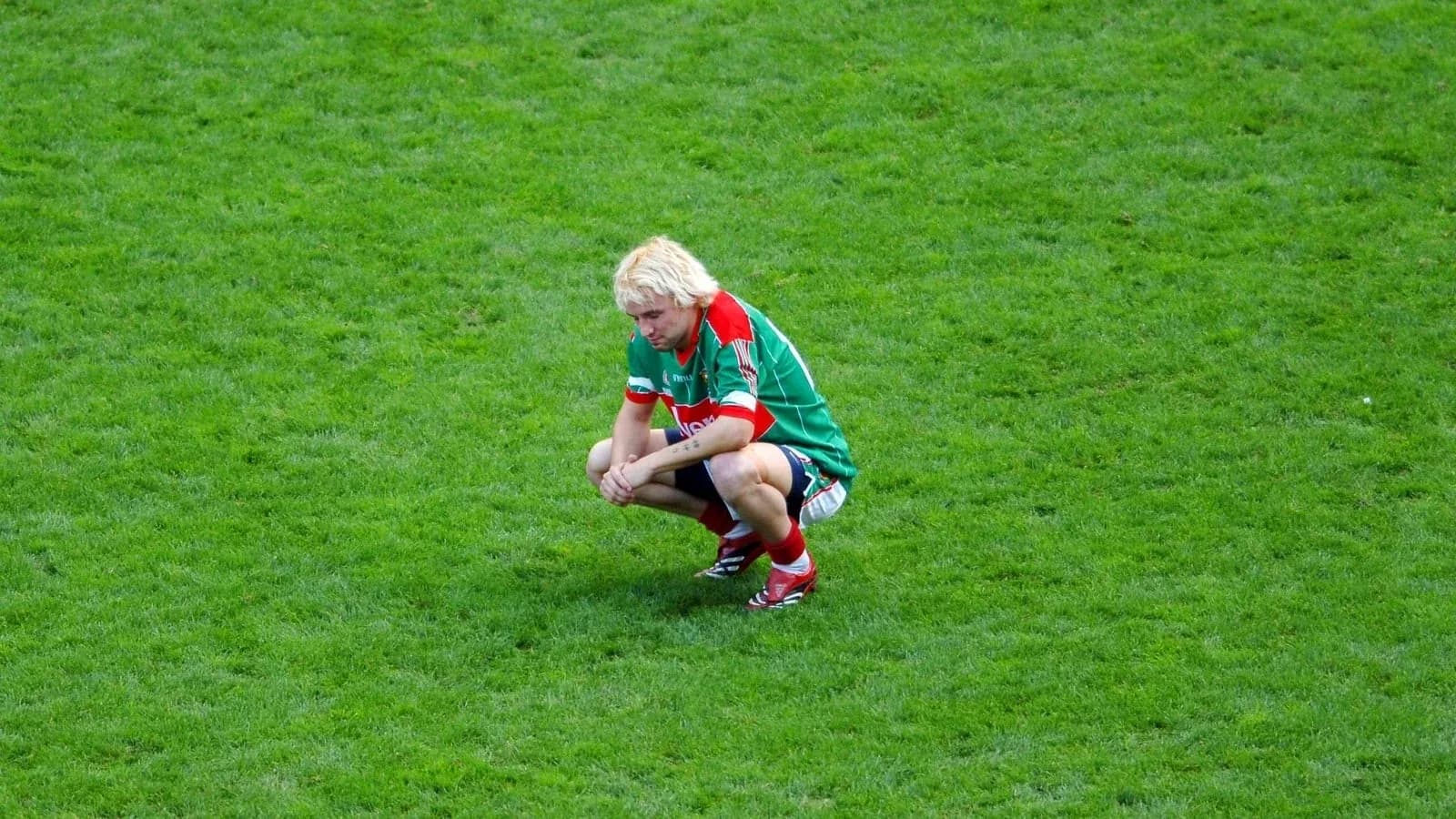 Player squatting on the field during a match Player squatting on the field during a match