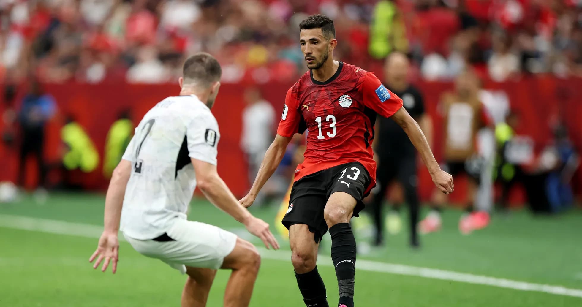 Player in red jersey dribbling past opponent in white Player in red jersey dribbling past opponent in white