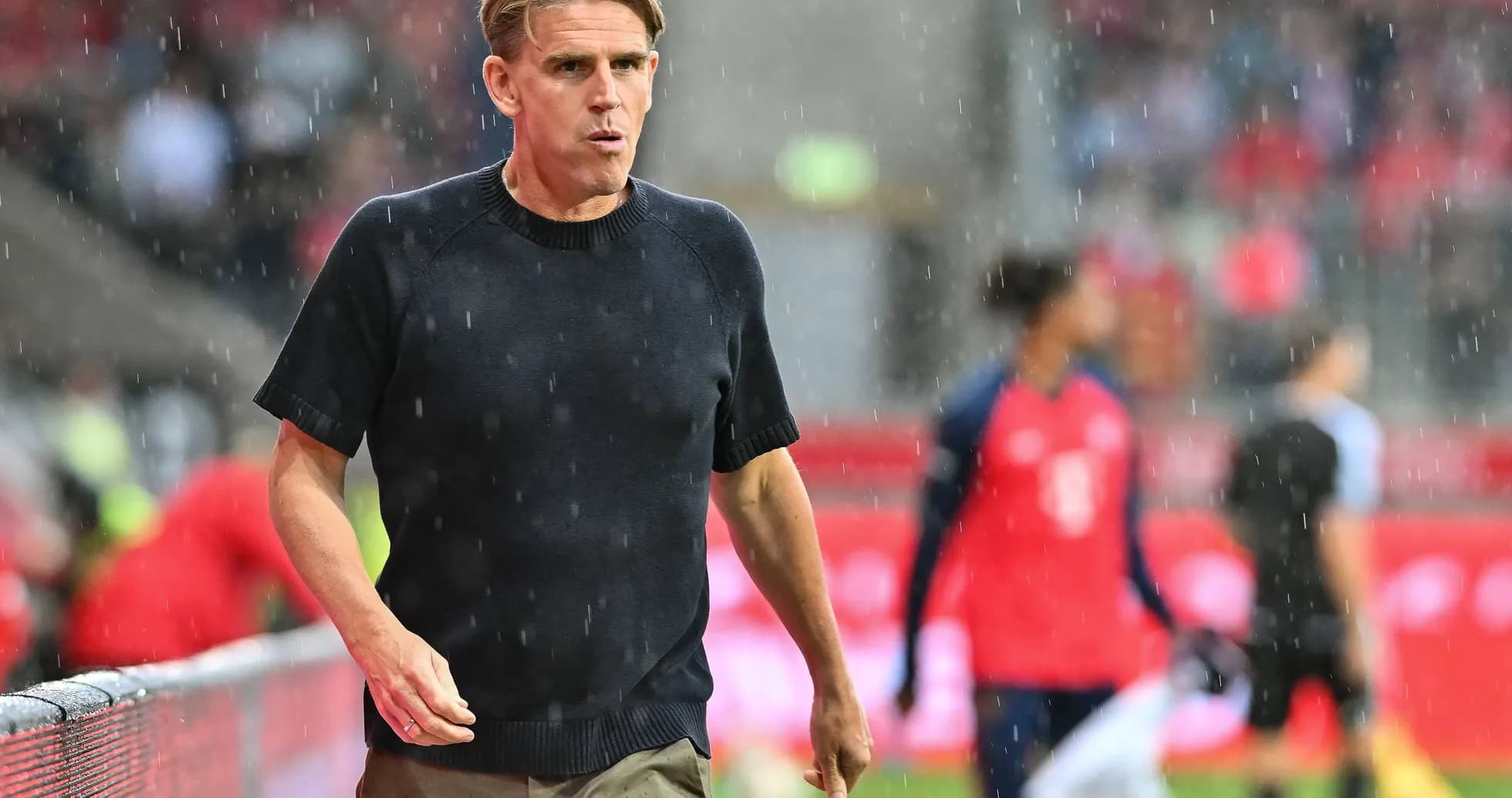 Coach walking along the sideline in rain Coach walking along the sideline in rain