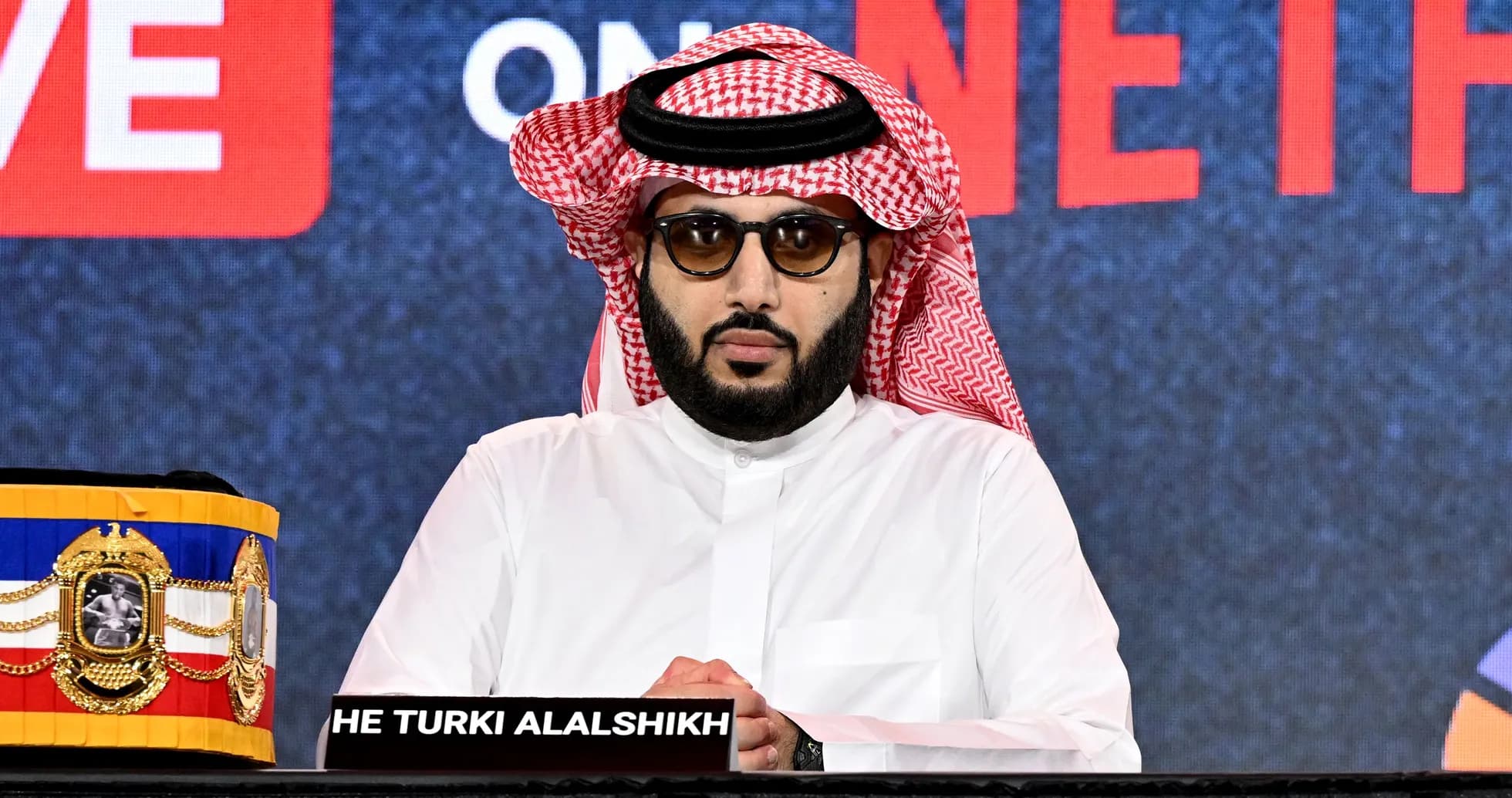 Man in traditional dress at press conference table Man in traditional dress at press conference table