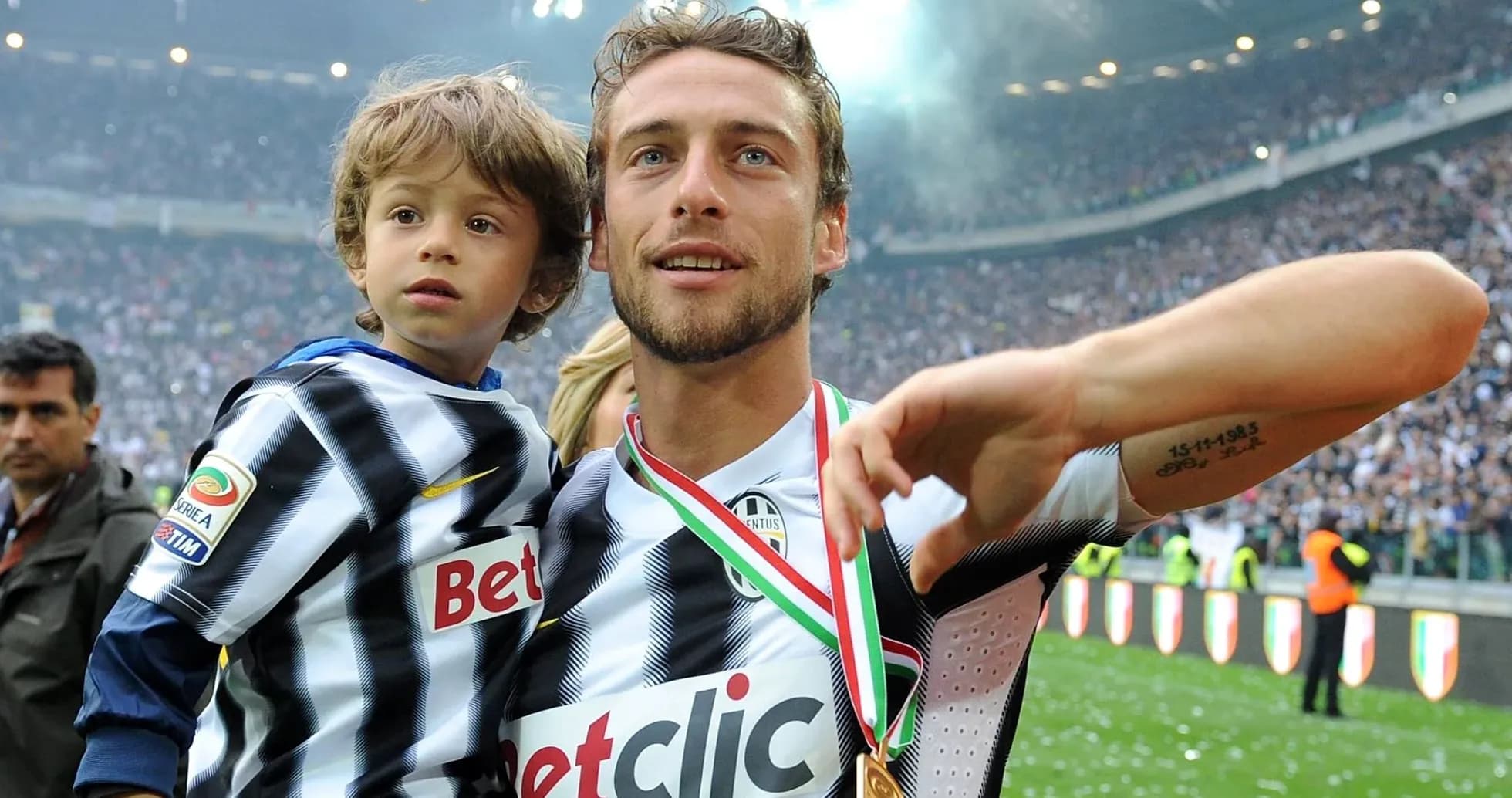 Player holding child with medal in stadium Player holding child with medal in stadium