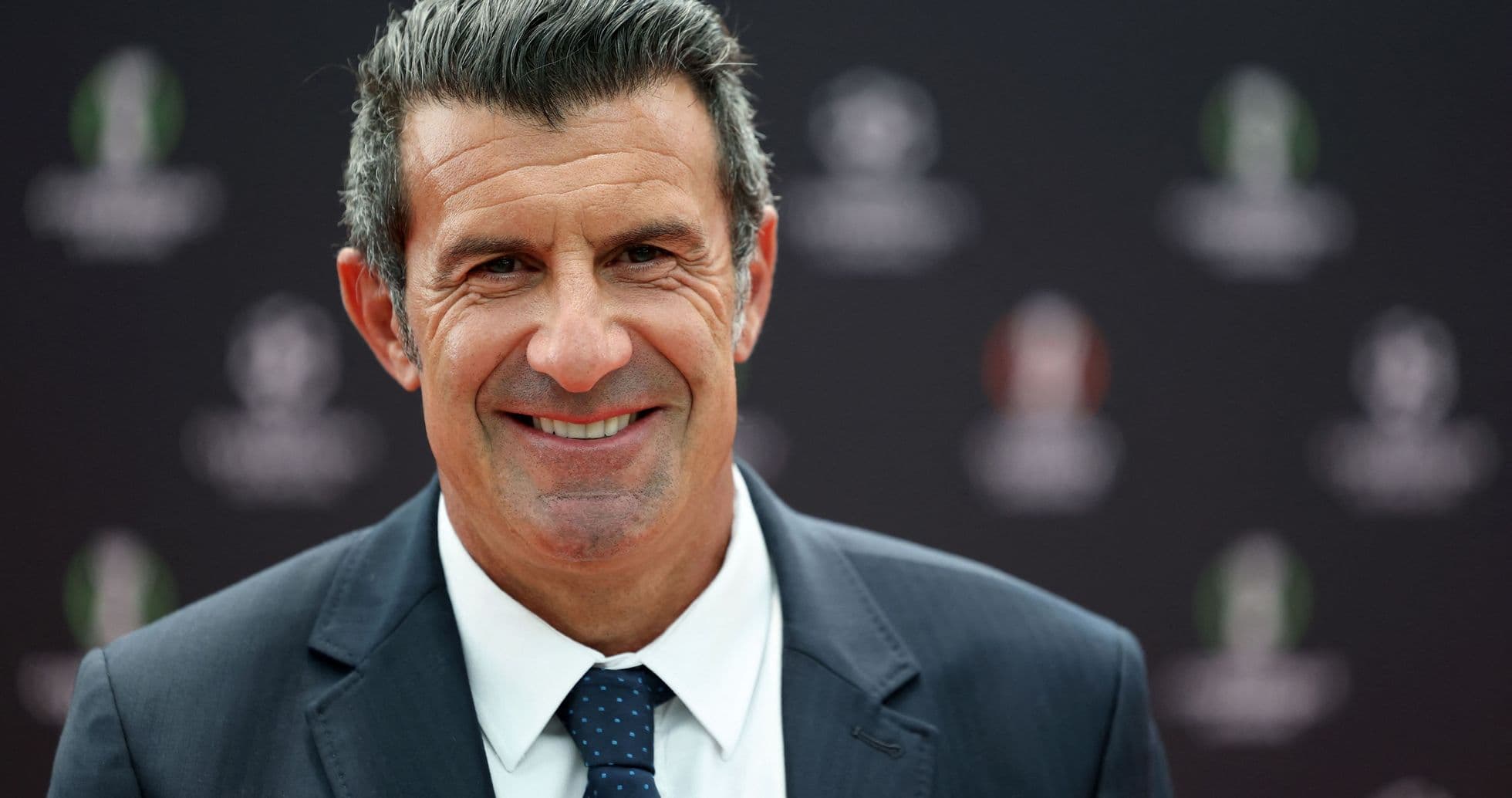Man in suit smiling at event backdrop Man in suit smiling at event backdrop