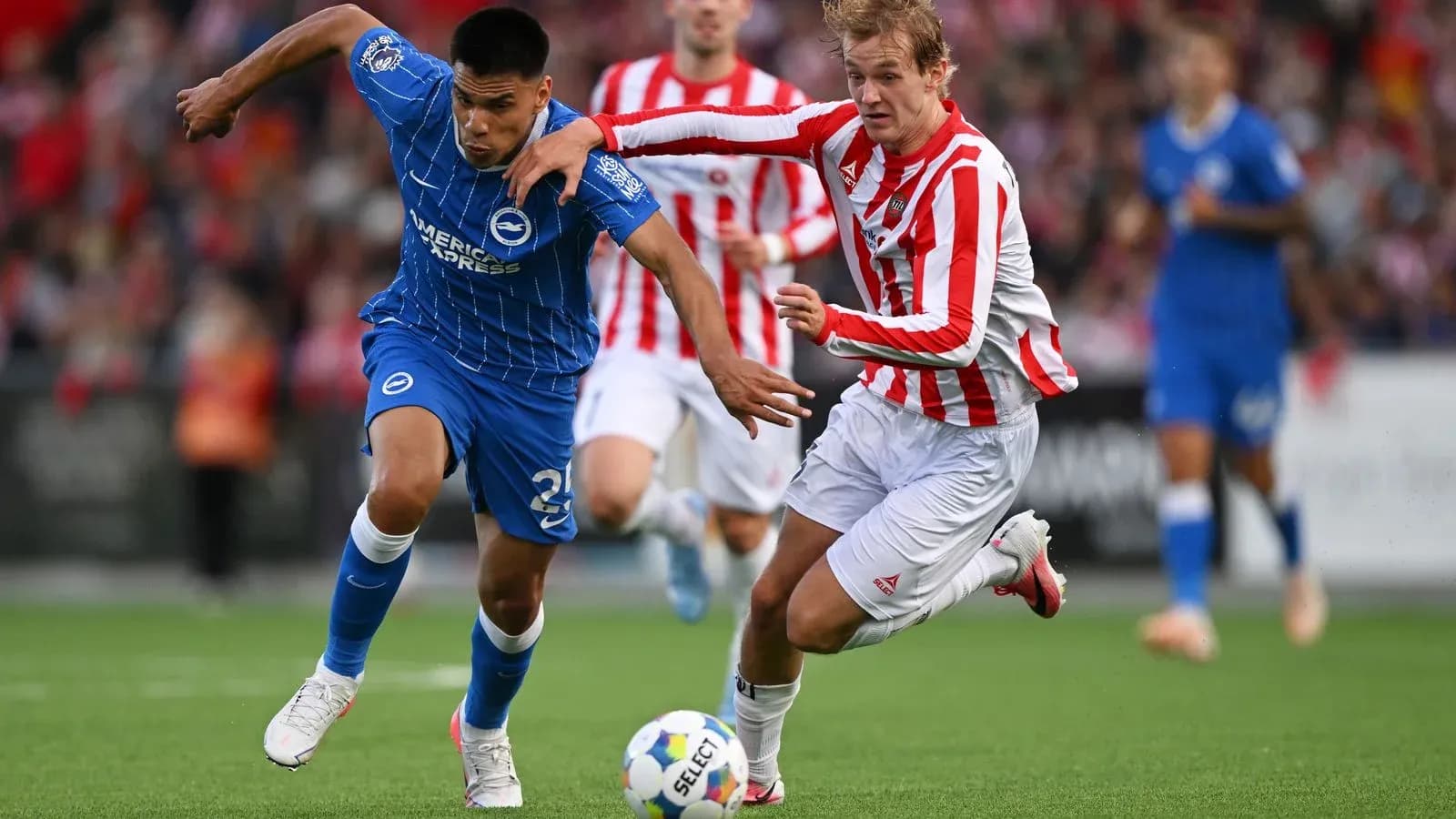 Player in blue jersey evading opponent in red stripes Player in blue jersey evading opponent in red stripes