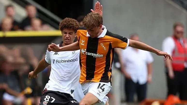 Player in black and orange jersey tackling opponent Player in black and orange jersey tackling opponent