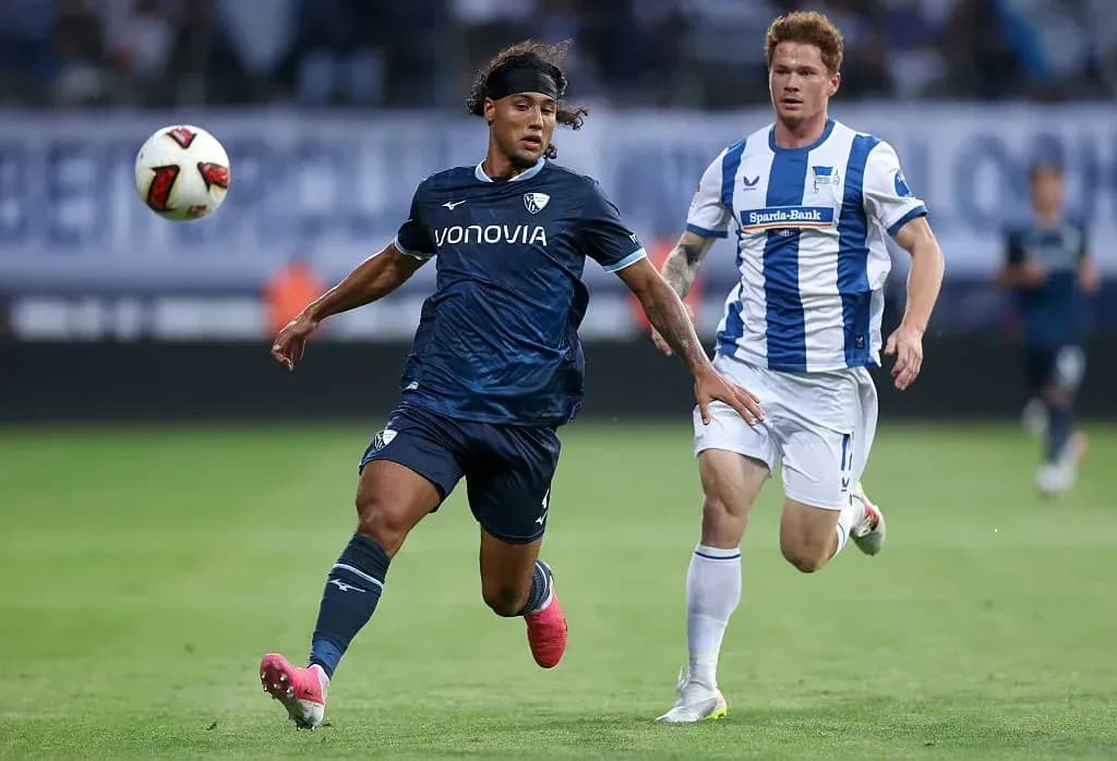 Player in blue jersey dribbling past opponent in white Player in blue jersey dribbling past opponent in white