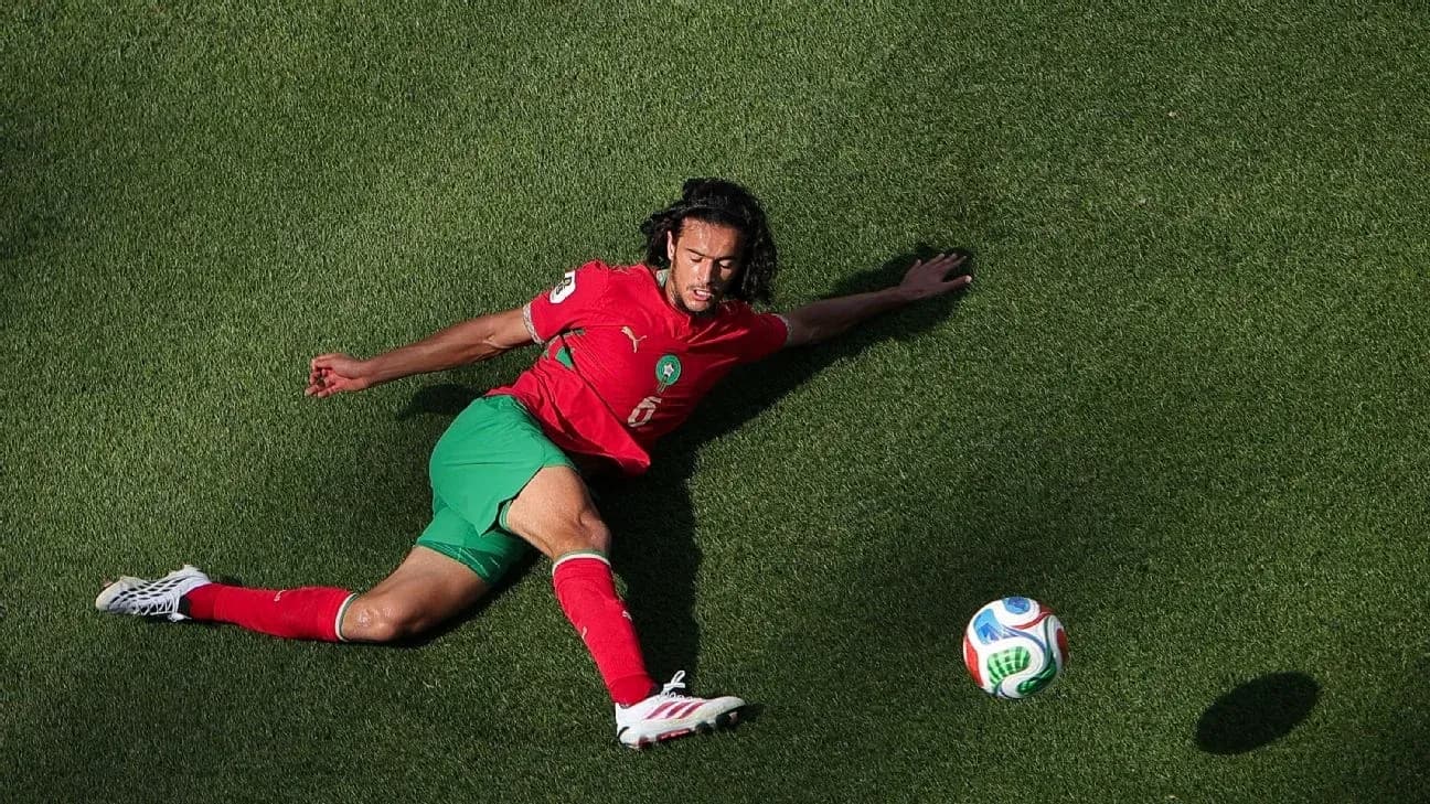Player in red and green uniform on grass field Player in red and green uniform on grass field