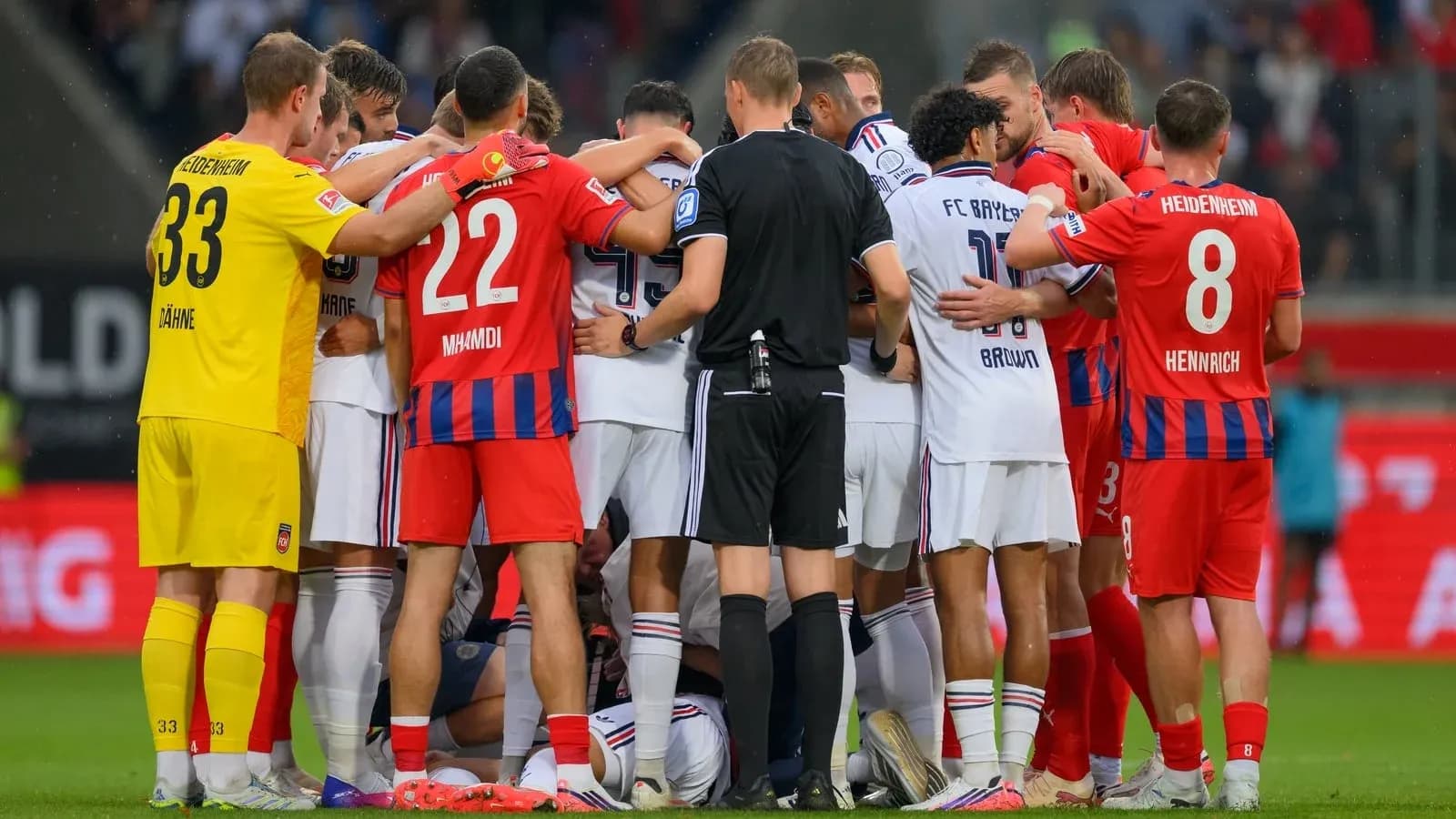 Players from both teams gathered around injured player Players from both teams gathered around injured player